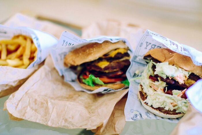 Burgers and fries wrapped in paper, illustrating dining out as a cost-saving sacrifice.