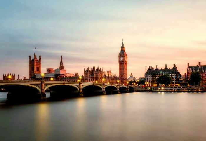 London cityscape at sunset with Big Ben and Westminster Bridge, highlighting luxury costs and travel.