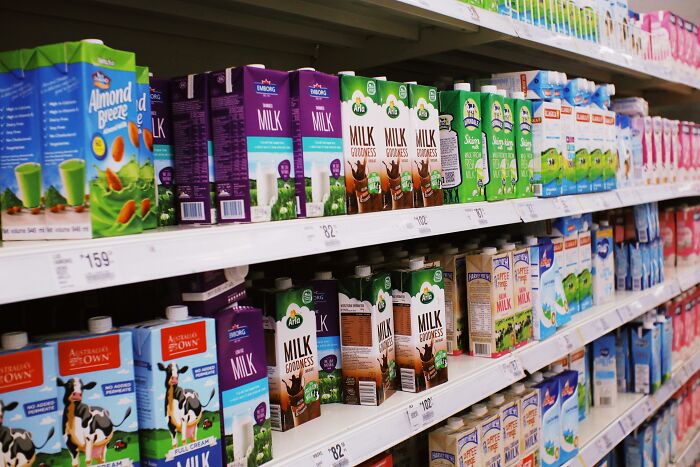 Grocery store aisle displaying various milk brands, highlighting things people avoid buying due to cost.