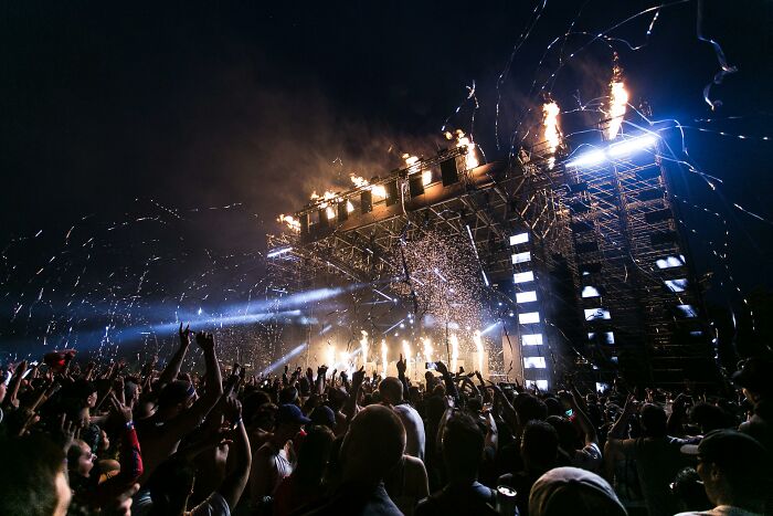 Crowd enjoying a concert with fireworks and bright lights, highlighting the cost-related decline in buying event tickets.