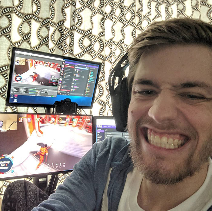 sodapoppin (Thomas “Chance” Jefferson Morris IV) wearing headphones grins widely in front of a gaming setup with multiple monitors displaying Twitch streams.