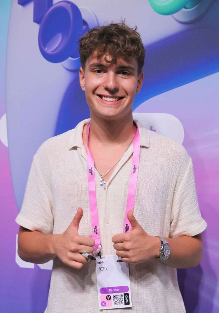 Young streamer Clix (Cody Conrod) smiling with thumbs up, wearing a pink lanyard at a gaming event.