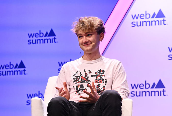 Famous streamer TommyInnit (Thomas Simons) at Web Summit, wearing a graphic white shirt, discussing streaming trends.