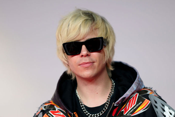 Blonde-haired Twitch star Rubius (Rubén Doblas Gundersen) in sunglasses and a graphic jacket, showcasing the style of famous streamers.