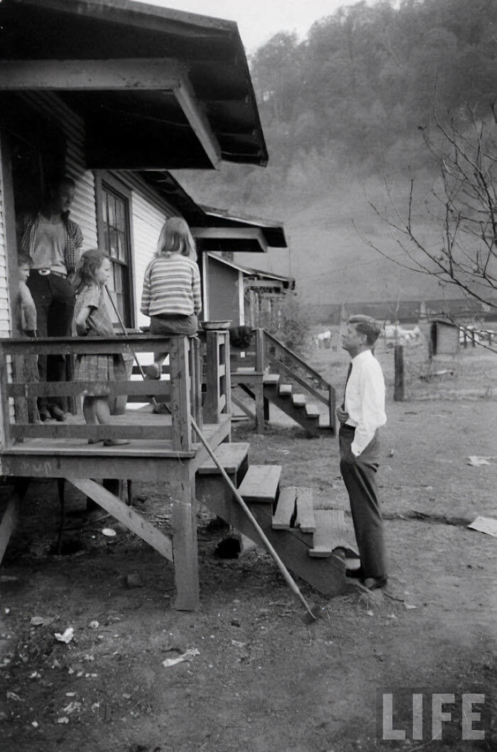 Group of children on porch with a man in historical attire standing in front.