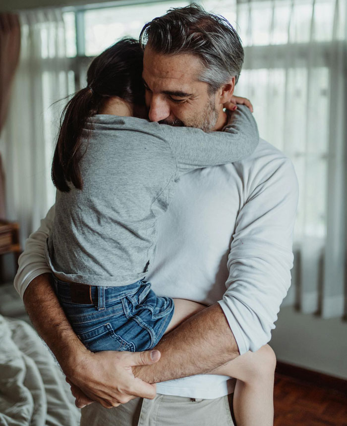 Father hugging daughter, emphasizing priority on her safety, health, and happiness.