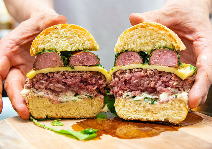 Hands holding a sliced burger with sprouts and meat, highlighting food bacteria risks.