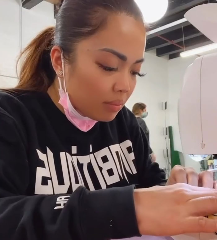 Woman focused on sewing in a workshop, supporting her lingerie business.