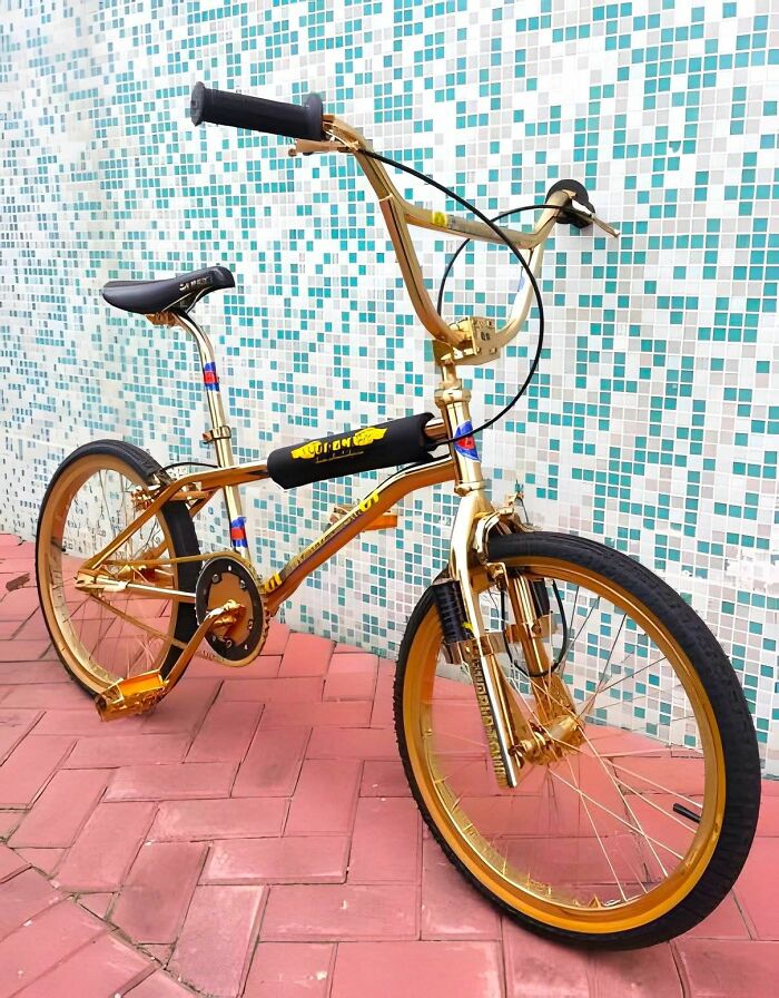 Gold vintage BMX bike, emblematic of Gen X nostalgia, leaning against a tiled wall.