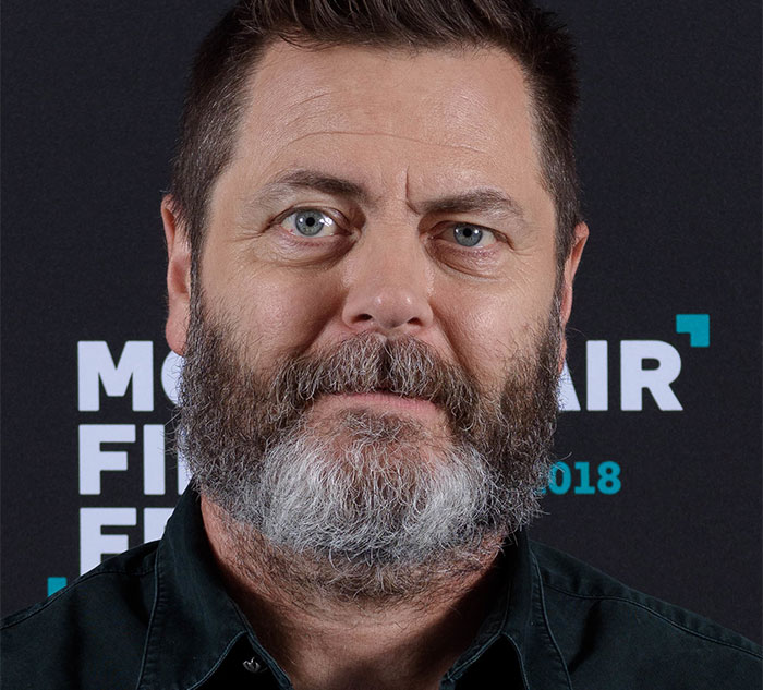 Man with a beard in front of a film festival backdrop, representing celebrities known for being nice.