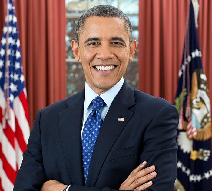 Smiling celebrity in a suit, with arms crossed, standing in a formal setting, showcasing nice personality traits.