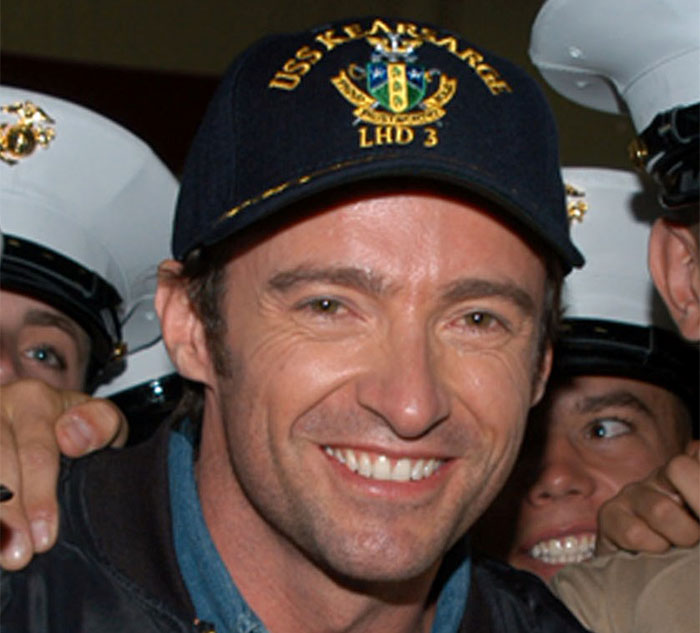 Celebrity smiling in a baseball cap, surrounded by people in military uniform, exemplifying nice behavior.