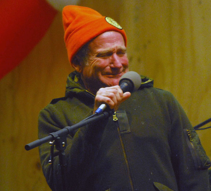 Man in a red hat smiling at a microphone, representing celebrities who are nice.