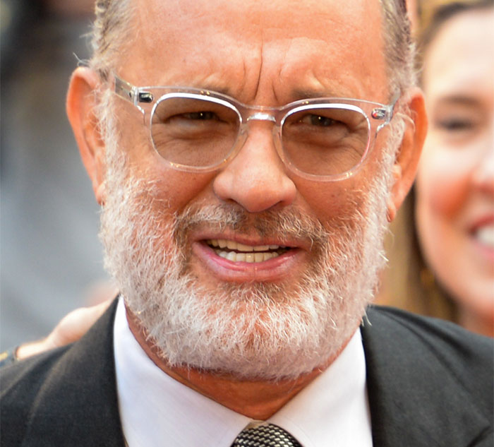 A celebrity with glasses and a beard smiling at an event, showcasing kindness in real life.