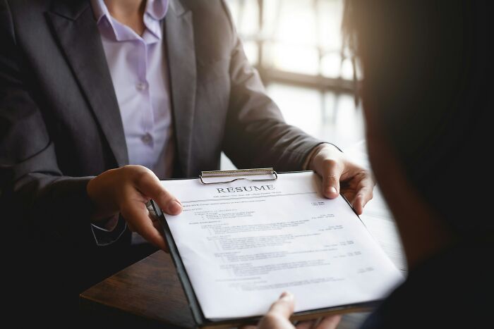 Person in a suit handing over a resume to another individual, highlighting career red flags noted by HR specialists.