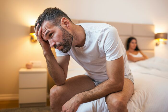 Man appearing pensive sitting on bed, conveying emotions related to savage and revengeful job exits.