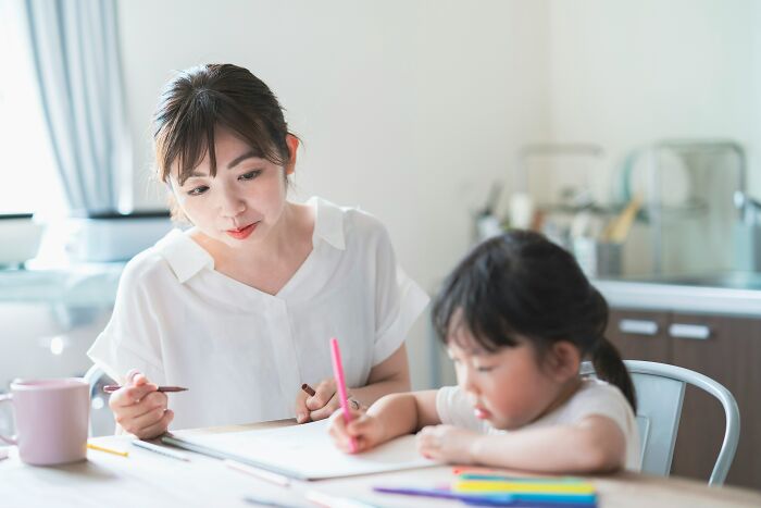 Parent and child drawing together at a table, focusing on creativity and connection.