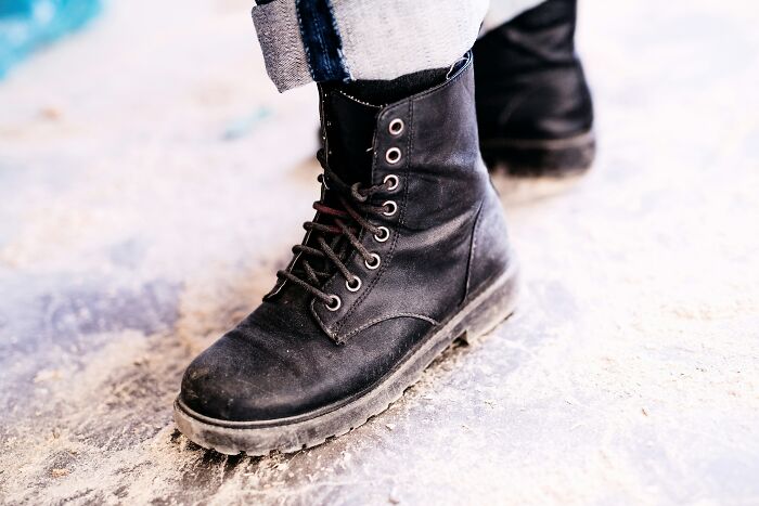 Black leather boots on concrete, highlighting expensive items worth spending money.