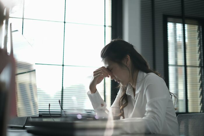 Woman in an office looking stressed, possibly planning a savage and revengeful job exit.