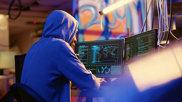 Person in a blue hoodie at a computer, possibly involved in background check related to social security numbers.