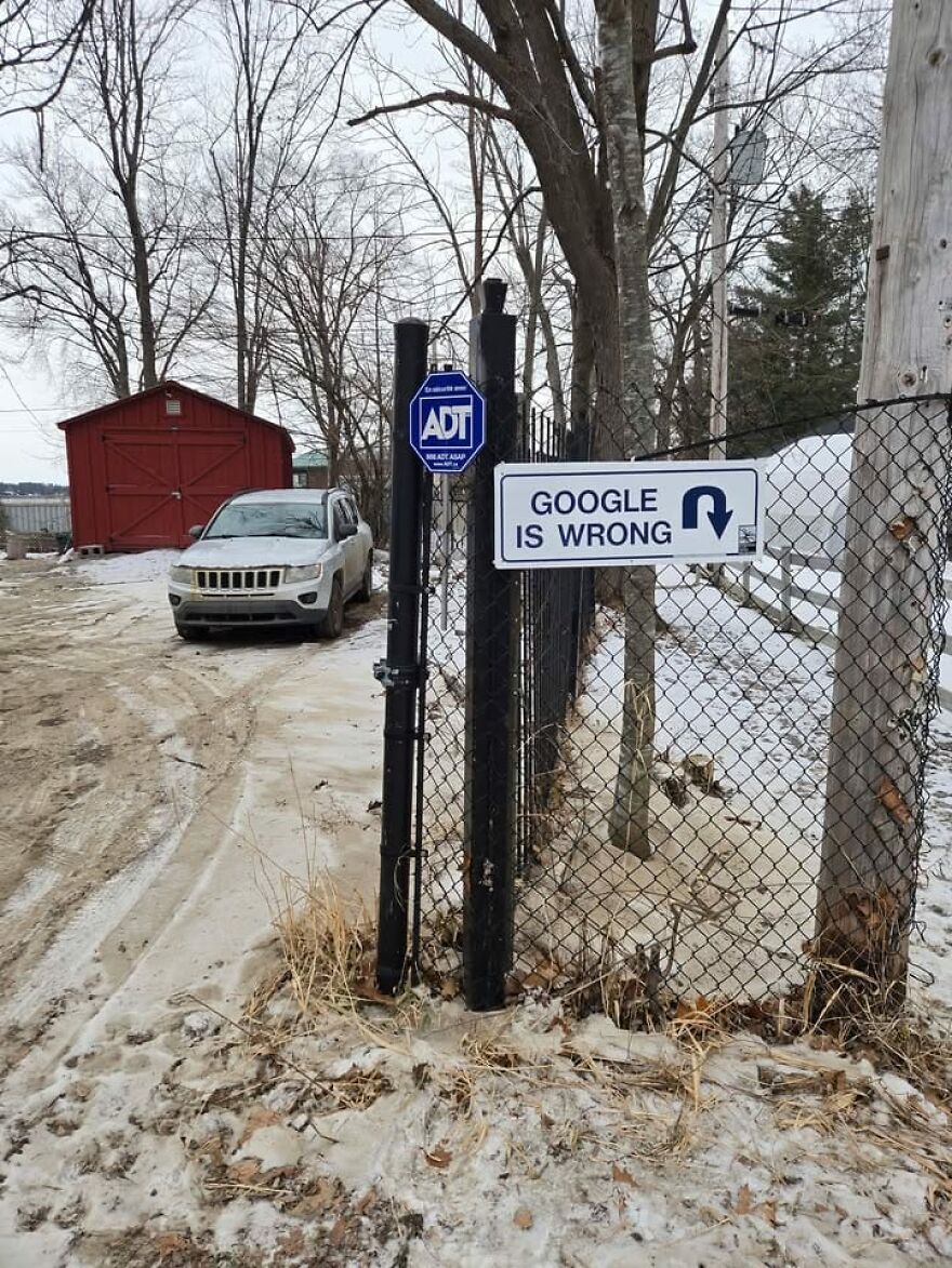 Sign on a snowy road says "Google is wrong" with an arrow, next to a parked car and trees, highlighting strange Google Earth finds.