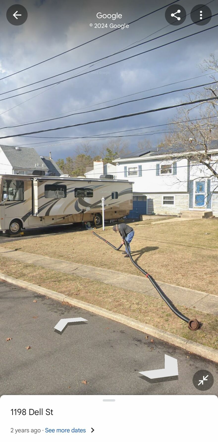 Strange things on Google Earth: person with long hose near RV on residential street, cloudy sky overhead.