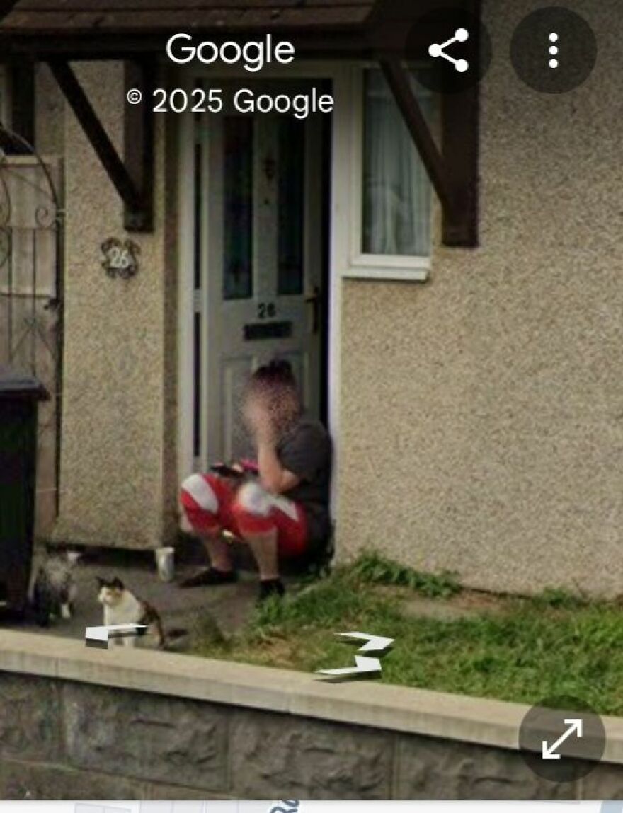 Strange Google Earth discovery: person sitting by a door with a cat nearby.