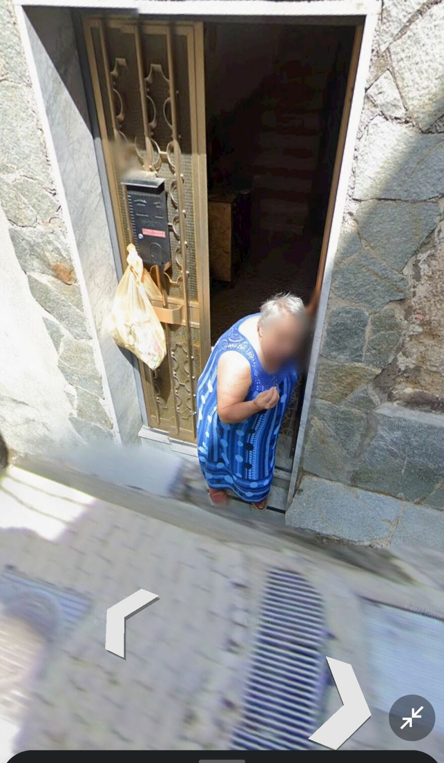 Person in a blue dress at a doorstep, captured on Google Earth.