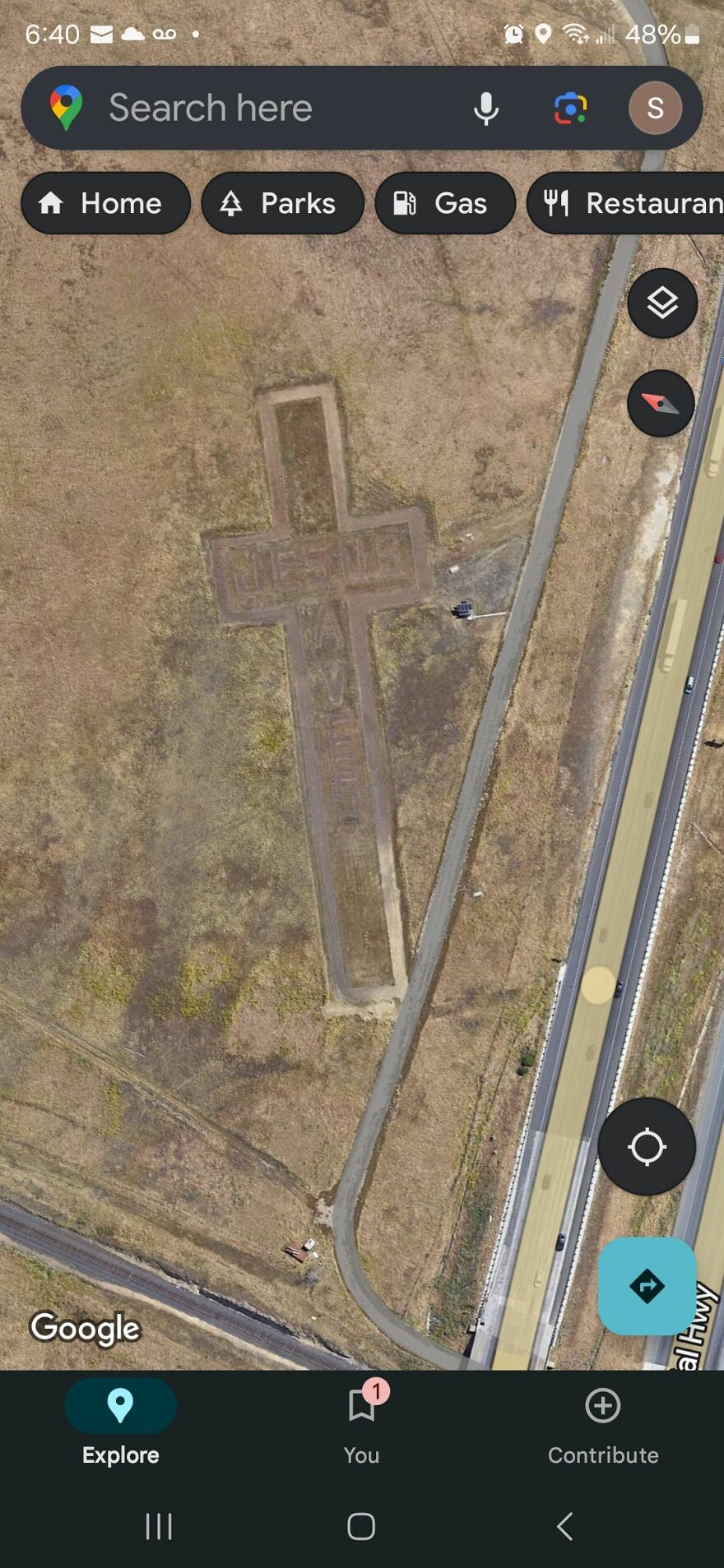 Strange cross-shaped formation with text "JESUS SAVES" discovered on Google Earth near a road.