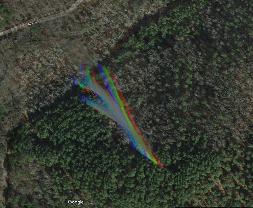 Google Earth image showing a multicolored, rainbow-like anomaly over a forested area, found by users.