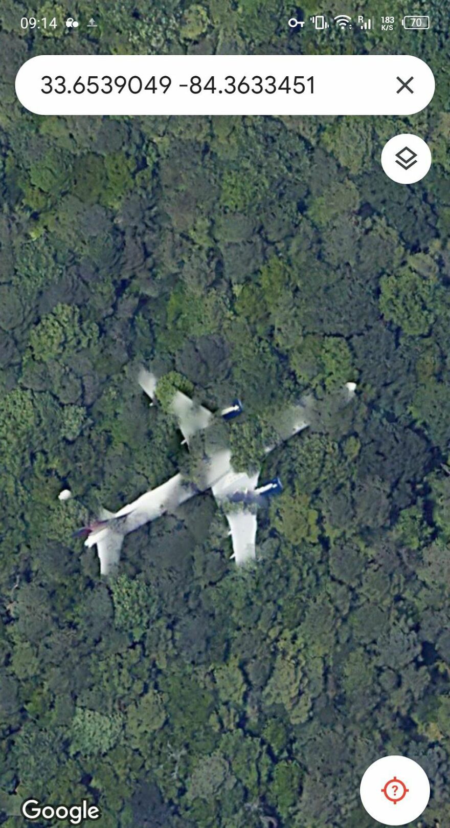 Strange airplane shadow spotted on Google Earth hidden within dense forest, featuring mysterious coordinates.