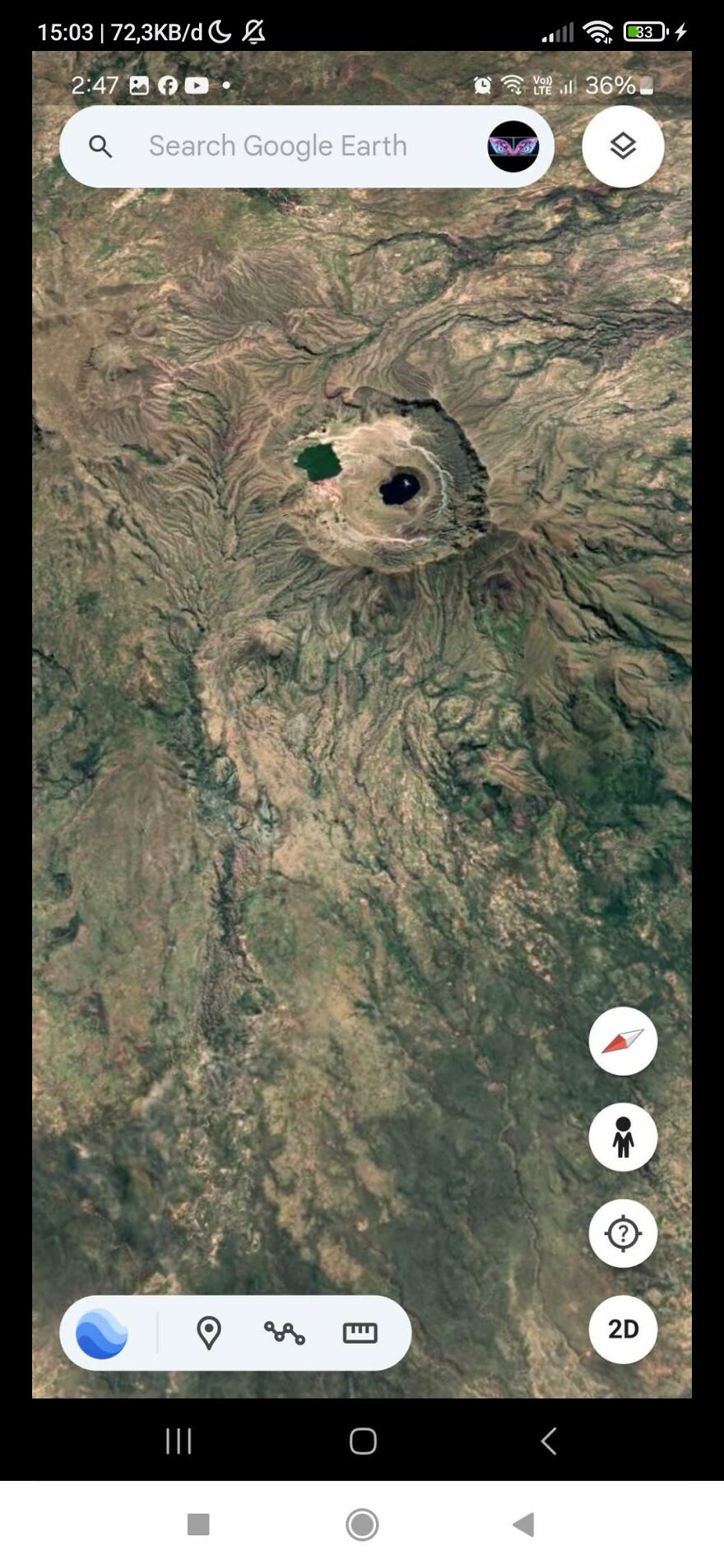 Google Earth view of a peculiar crater formation surrounded by rugged terrain.