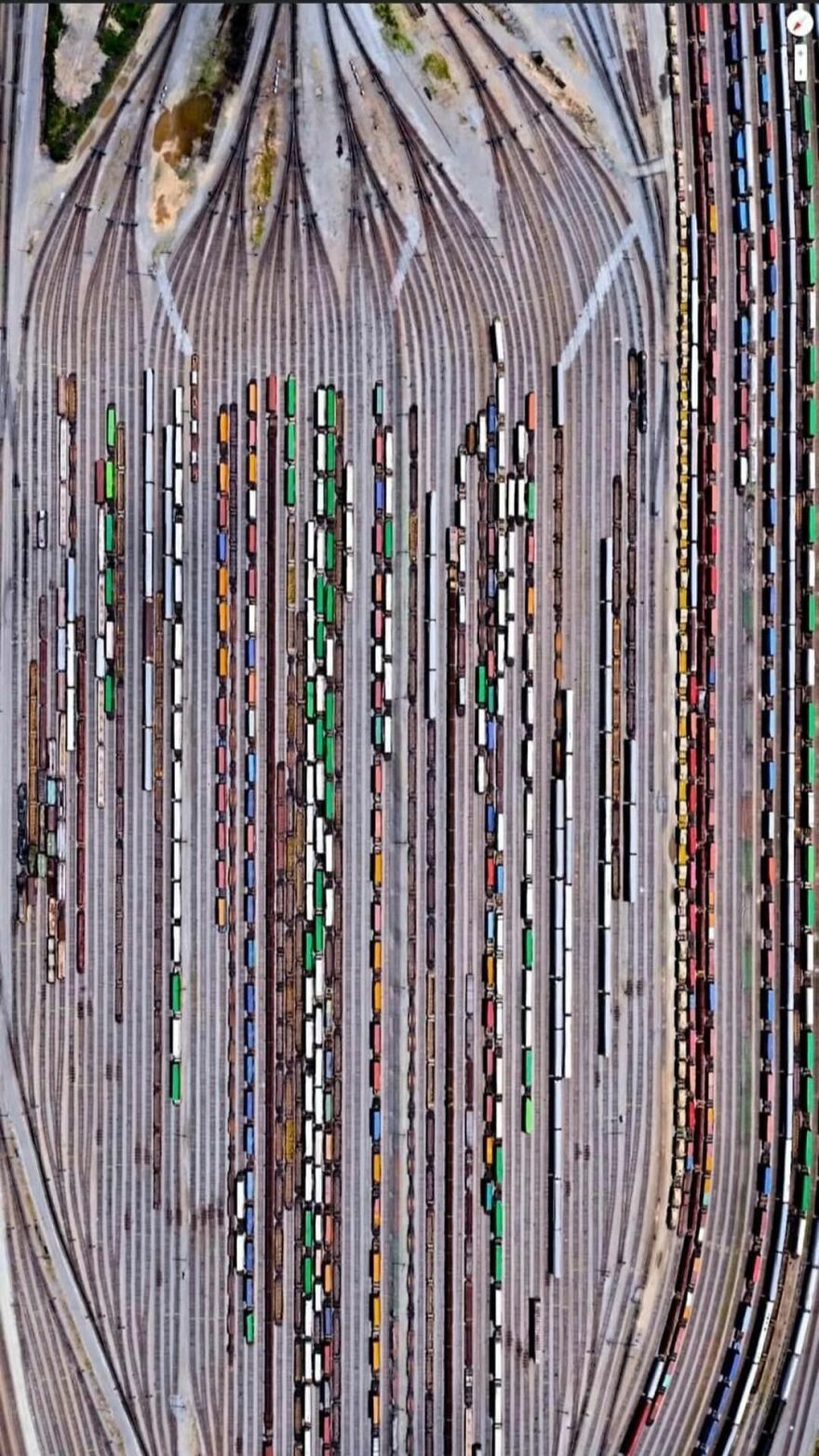 Aerial view of colorful train cars on tracks, a strange sight discovered on Google Earth.