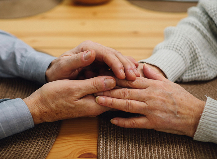 Hands holding each other on a wooden table.