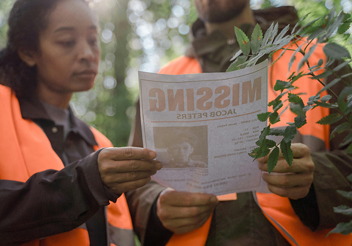 Search team members reviewing a missing person flyer in an outdoor setting.