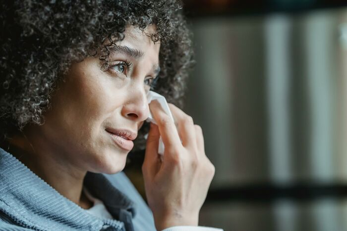 Woman wiping tears, looking distressed, possibly upset over a silverware drama.