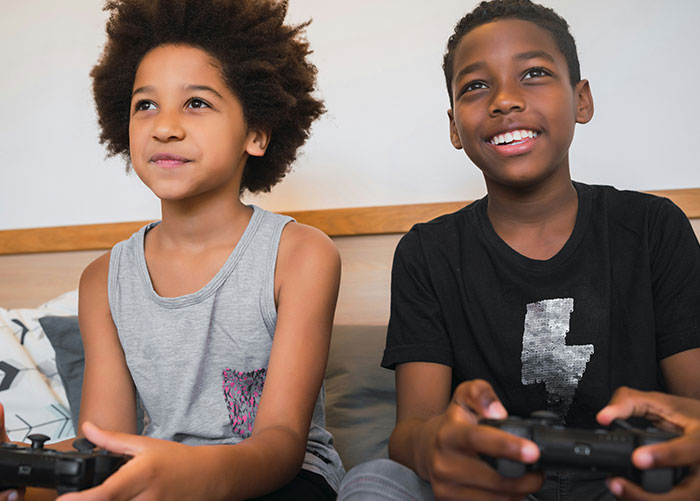 Two children playing video games, illustrating the concept of wealthy people's ordinary experiences.