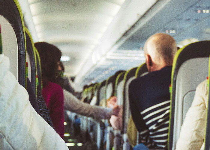 People seated inside an airplane, engaging in conversation, depicting ordinary moments among wealthy people.