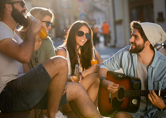 Wealthy people enjoying a sunny afternoon, chatting and playing guitar outdoors.