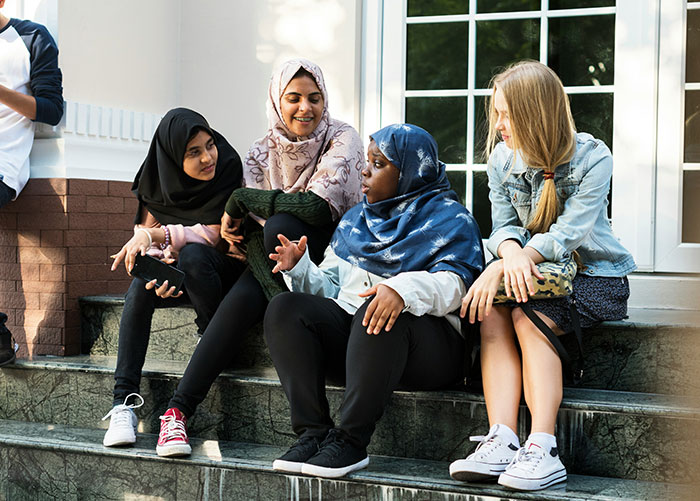 A group of friends sitting on steps, enjoying a casual conversation outside a building.