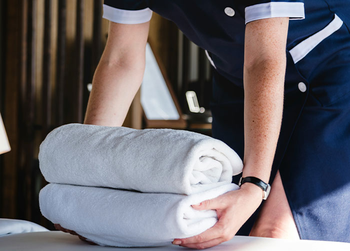 Person in uniform folding towels, illustrating the concept of wealthy people and their ordinary perceptions.