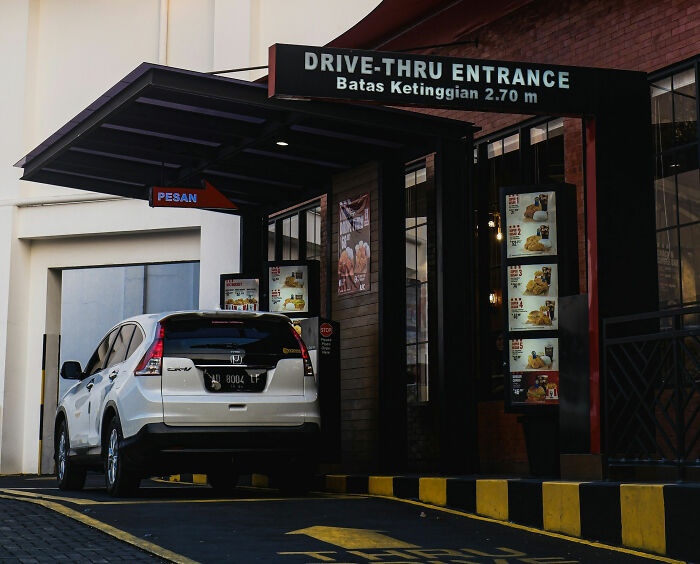 Car in drive-thru entrance, highlighting modern social norms in daily life.