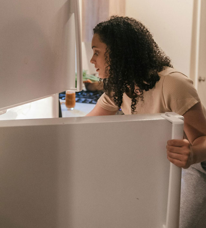 Woman looking inside a refrigerator, relating to food and roommates.