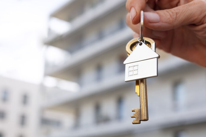 Person holding house key, symbolizing unaffordable housing for the middle class.