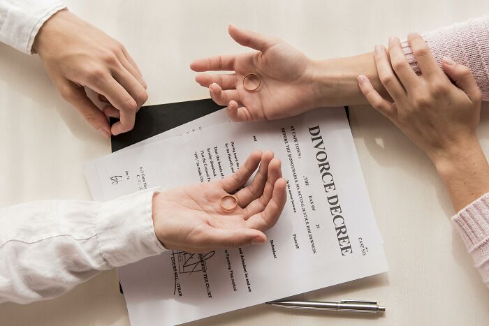 Divorce agreement on a table with two hands exchanging wedding rings, symbolizing rising unaffordability for the middle class.