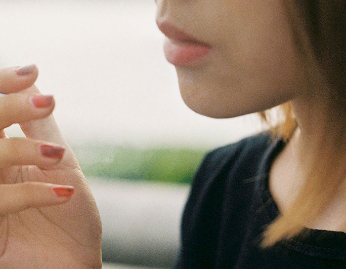 Close-up of a thoughtful person with painted nails, symbolizing life lessons realized too late.