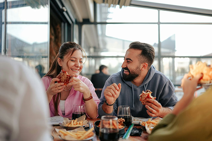 A man and woman enjoying a meal together, smiling in a bright restaurant, reflecting on life lessons learned too late.