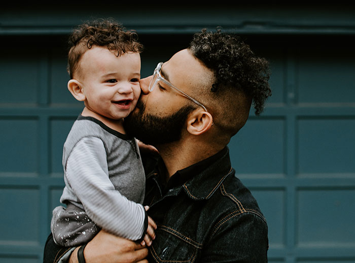 Father kissing child on the cheek, illustrating life lessons about cherishing moments.