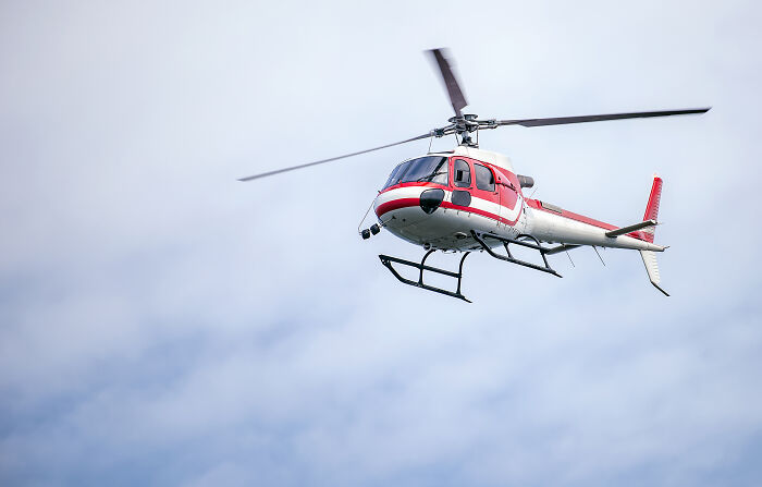 A red and white helicopter flying in a clear sky, symbolizing dramatic and revengeful job exits.