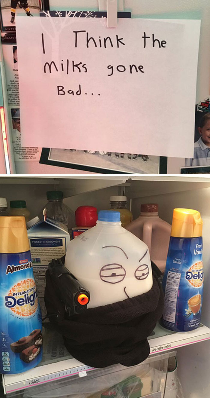 Hilarious milk jug in fridge with drawn face and toy gun, surrounded by creamer bottles, beneath note about bad milk.